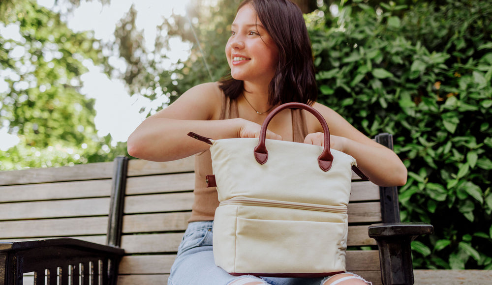 young girl sitting on bench opening her insulated lunch bag