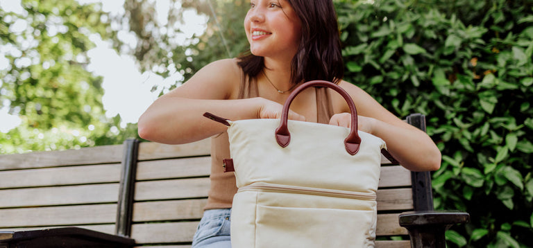 young girl sitting on bench opening her insulated lunch bag