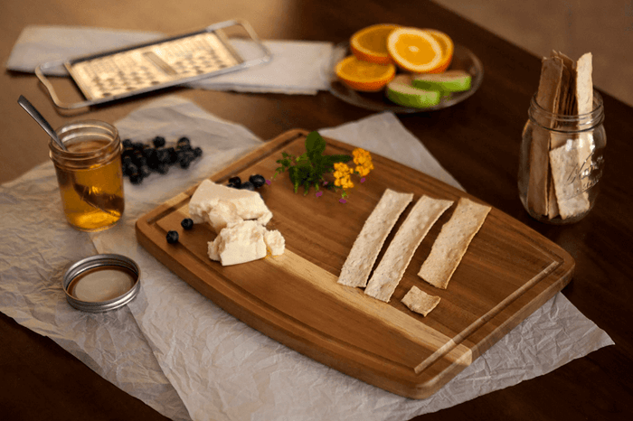 Ovale cutting board with cheese and crackers.